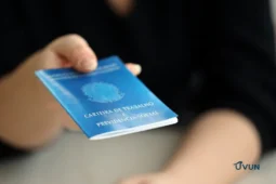 Trabalhadora segurando carteira de trabalho, representando o FGTS e os direitos do trabalhador.