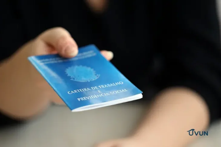 Trabalhadora segurando carteira de trabalho, representando o FGTS e os direitos do trabalhador.