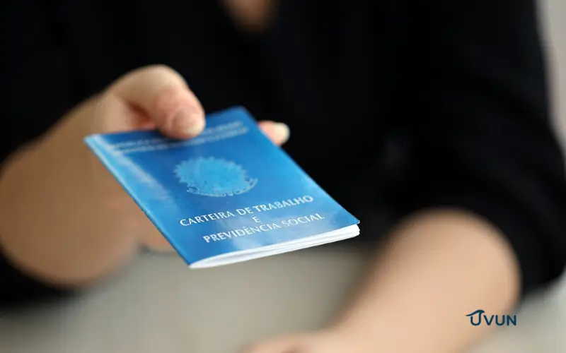 Trabalhadora segurando carteira de trabalho, representando o FGTS e os direitos do trabalhador.