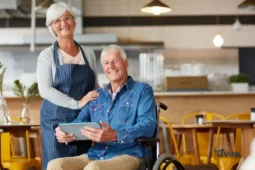 Homme en fauteuil roulant accompagné d’une femme, illustration de l’AAH.