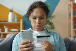 Femme consultant son téléphone avec une carte de crédit renouvelable.