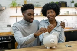 Couple déposant des pièces dans une tirelire pour épargner en couple.