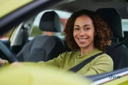 Femme souriante au volant de sa voiture, illustrant l'aide permis de conduire